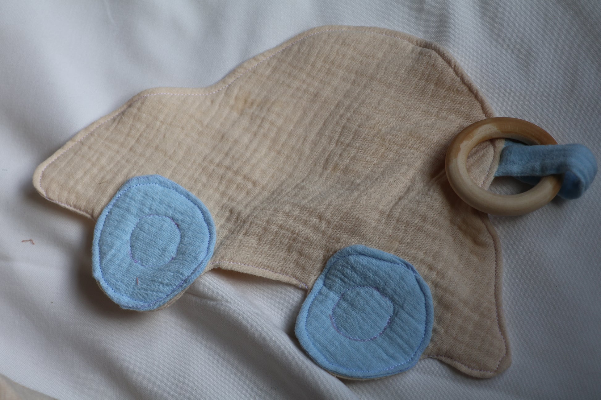 Baby teething ring with blue fabric and wooden ring on a white background